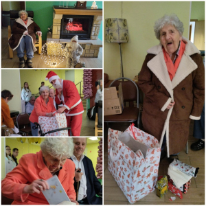 Rozdawanie prezentów na oddziale 3A. Mieszkanka pozuje do zdjęcia z podarunkami od Mikołaja.