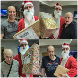 Rozdawanie prezentów na oddziale 4A. Mieszkaniec pozuje do zdjęcia z podarunkami od Mikołaja.