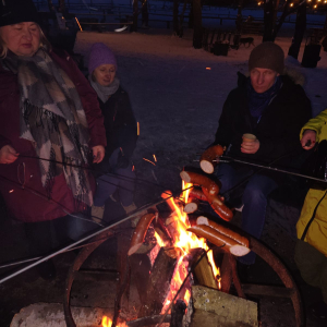Uczestnicy kuligu podczas pieczenia kiełbasek na ognisku.
