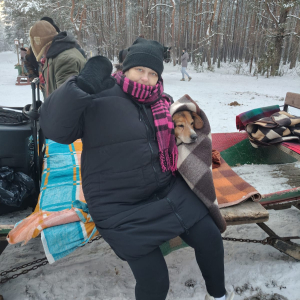 Uczestniczka kuligu z pieskiem na saniach.