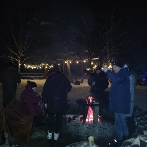 Mieszkancy pieką kiełbaski przy ognisku