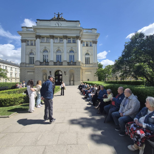 Uczestnicy wycieczki odpoczywają pod gmachem biblioteki na kampusie Uniwersytetu Warszawskiego
